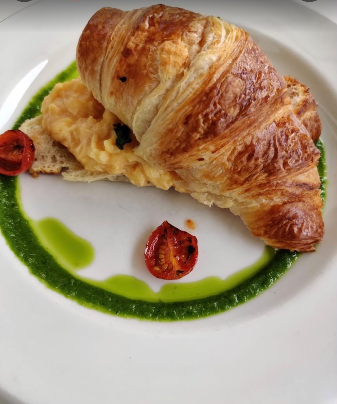 Buttery croissant with creamy scrambled egg and roast tomato