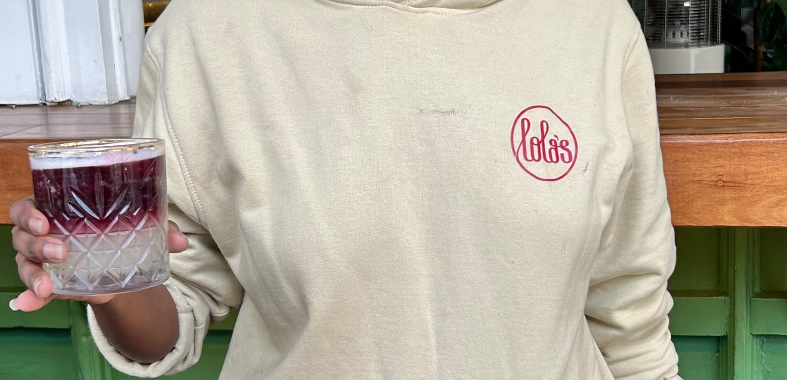 Lola's branded hoodie with a signature berry cocktail in hand