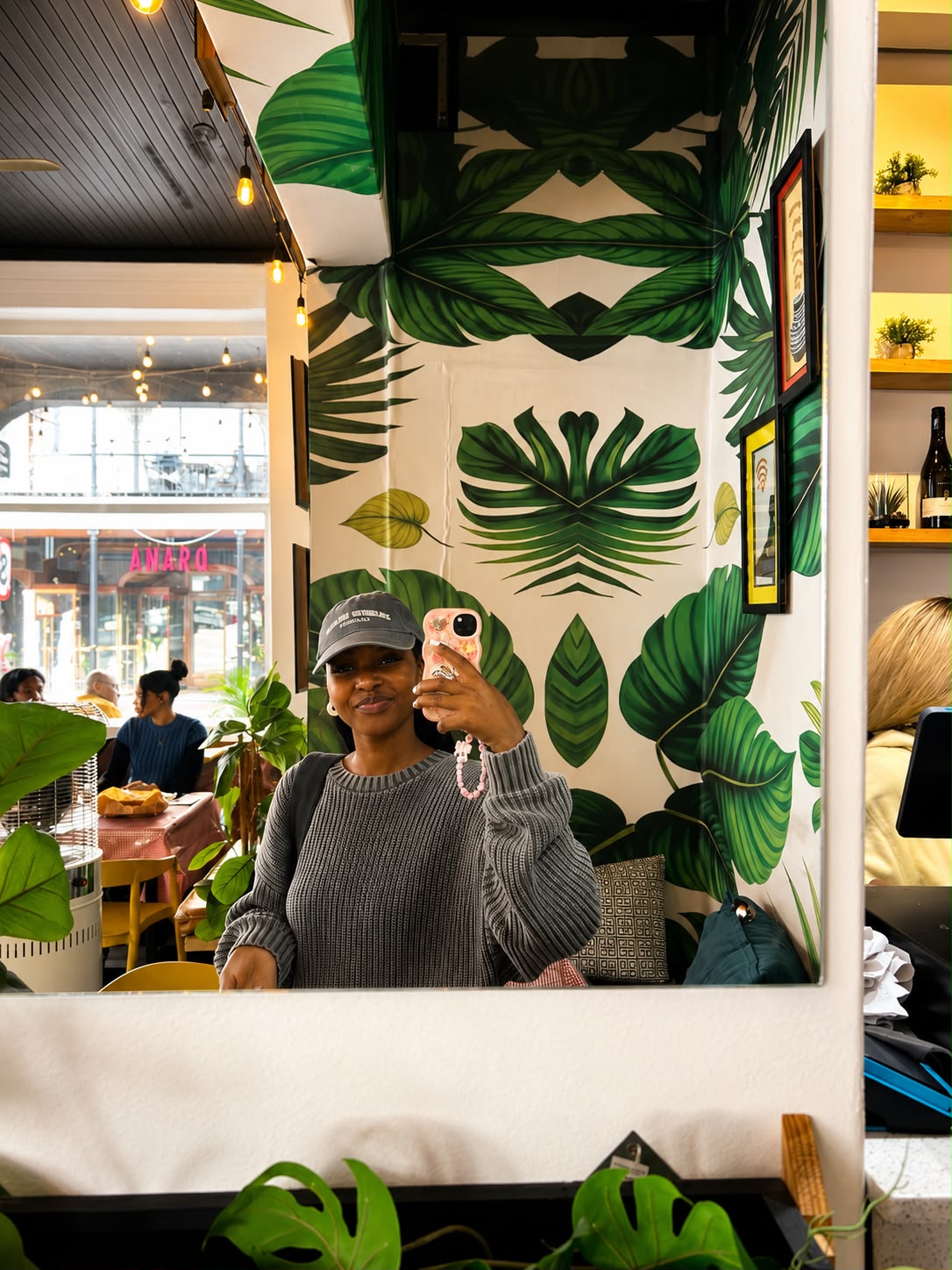 Guest in the mirror against the tropical leaf mural at Lola's